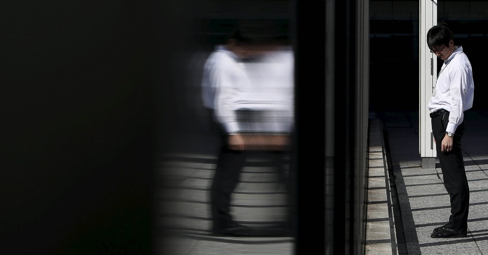 19.nov.2015 - Homem passa por parede de vidro em um distrito comercial em Tóquio, no Japão