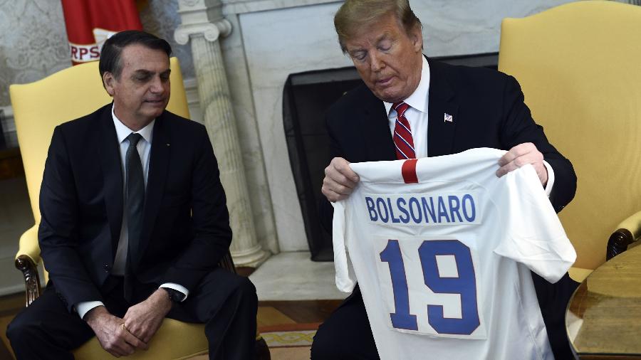 19.mar.2019 - Presidente dos EUA Donald Trump troca camisas de futebol com o presidente Jair Bolsonaro - Brendan Smialowski/AFP