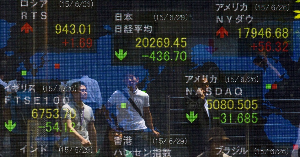 29.jun.2015 - Pessoas tem imagem refletida na tela de um painel eletrônico que mostra a média Nikkei do mercado em Tóquio, no Japão