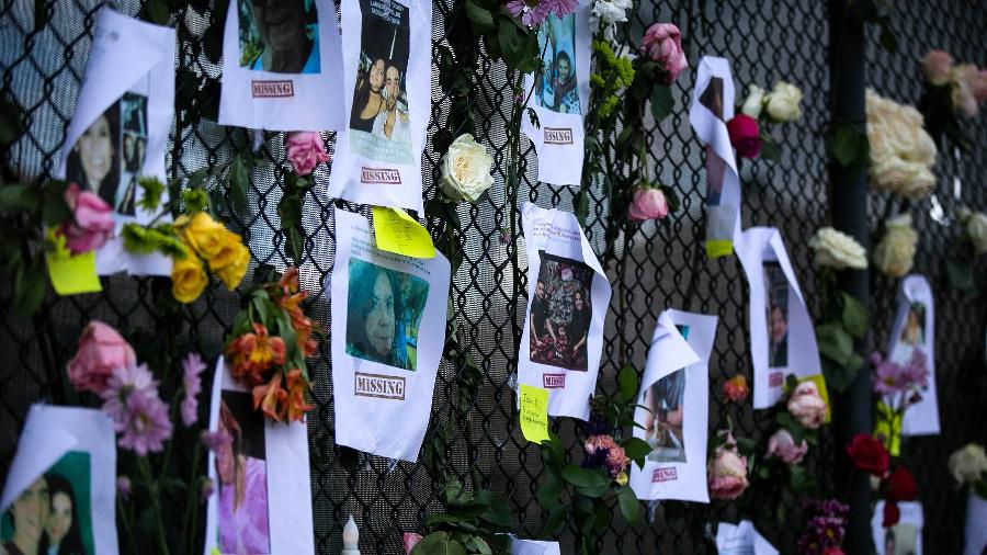 26.jun.2021 - Fotos dos moradores desaparecidos são colocadas em memorial improvisado no local em que prédio desabou em Surfside, Flórida - Andrea Sarcos/AFP