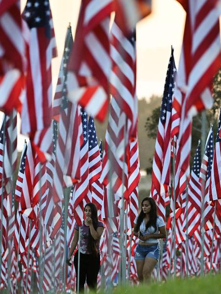 Pessoas caminham entre as bandeiras americanas expostas para comemorar as vidas perdidas no ataque terrorista de 11 de setembro - Robyn Beck / AFP