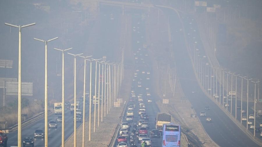 Veículos trafegam por uma estrada coberta de fumaça do incêndio que afeta o Parque Nacional de Brasília em Brasília em 16 de setembro de 2024