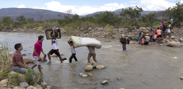 Colombianos carregam seus pertences enquanto atravessam o rio Tachira, próximo a Cucuta, na Colômbia, ao deixarem a Venezuela - Juan Pablo Cohen/La Opinión/Reuters