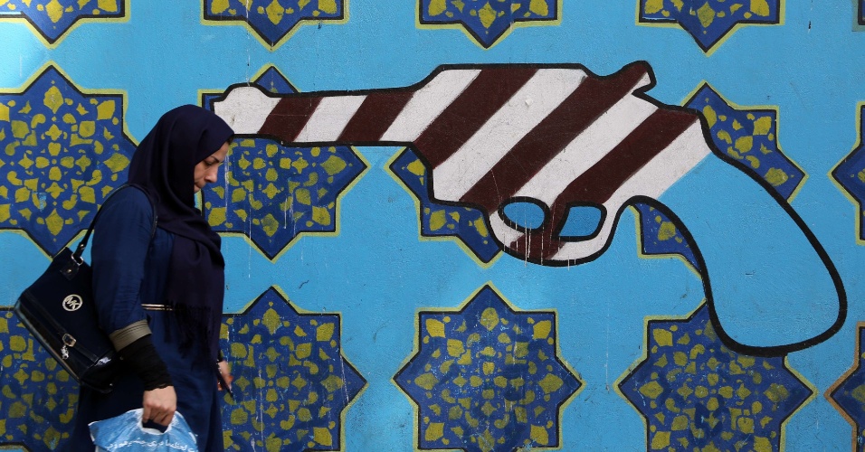 2.set.2015 - Mulher oberva um mural representando um revólver com as cores da bandeira nacional dos Estados Unidos na parede da antiga embaixada dos EUA em Teerã, no Irã