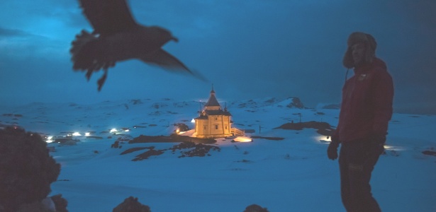 Cientista caminha com a igreja ortodoxa russa ao fundo, em área de bases da Antártida - Daniel Berehulak/The New York Times