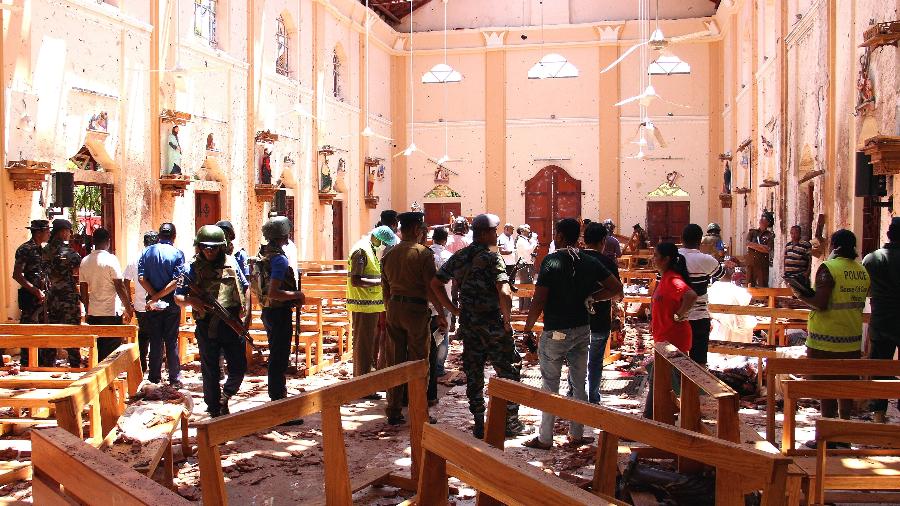 21.abr.2019 - Agentes de segurança do Sri Lanka caminham pelos escombros após explosão em igreja  - AFP
