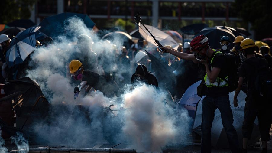 Manifestantes tentam se livrar de gás lacrimogêneo disparado pela polícia no distrito de Tai Po durante uma greve geral em Hong Kong em agosto - Philip Fong/AFP