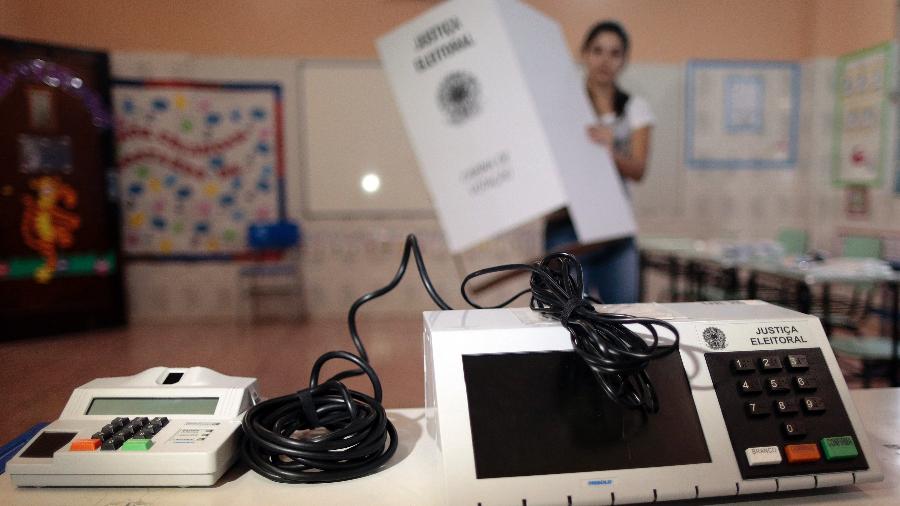 Funcionária da Justiça Eleitoral instala urna eletrônica em local de votação - Ueslei Marcelino