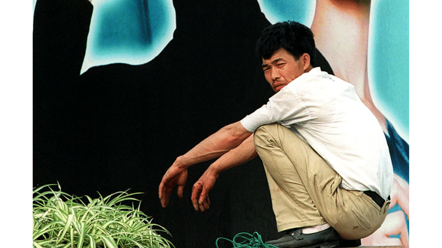 Homem agachado em rua de Xangai; posição é comum entre crianças e adultos asiáticos