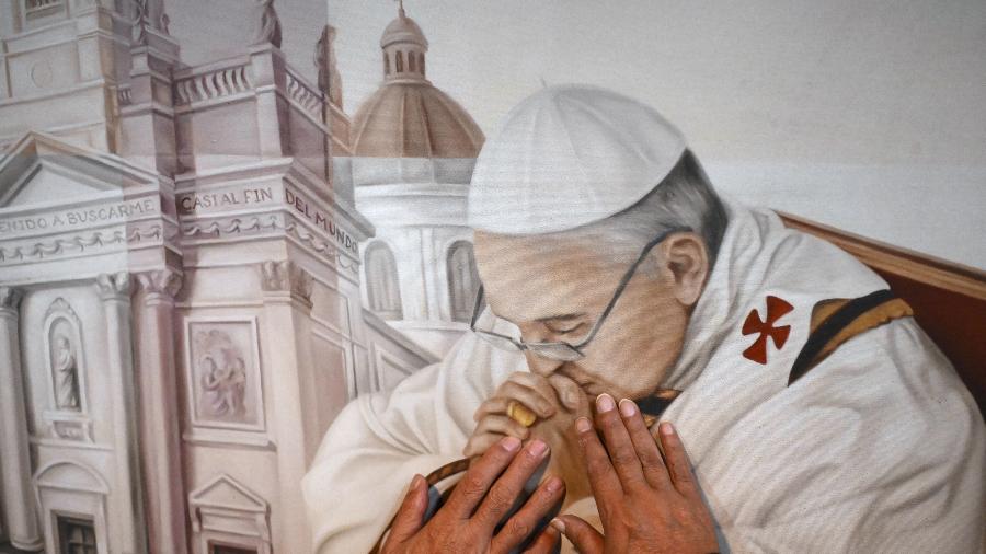 Fiel toca pintura representando o papa Francisco na Basílica de São José de Flores, em Buenos Aires, após sua morte - Luis Robayo/AFP 21.abr.2025