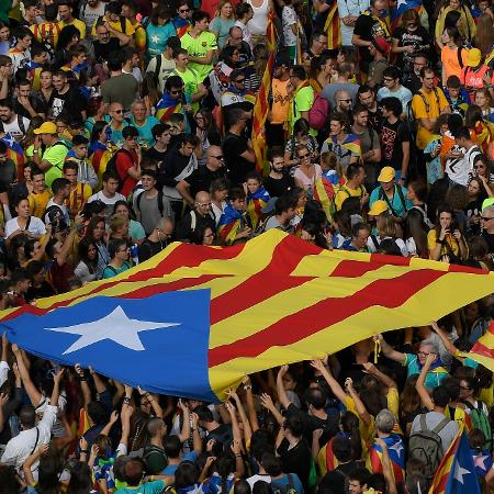 Manifestantes seguram bandeira pró-independência da Catalunha em Barcelona - Lluis Gene/AFP