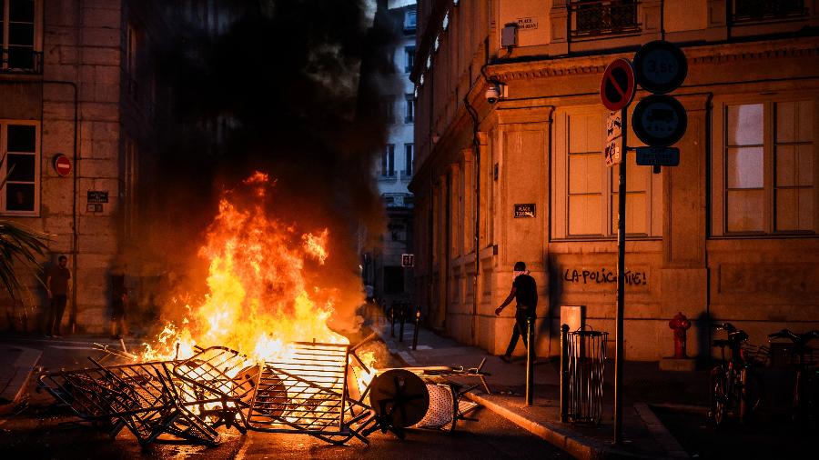30.jun.23 - Fumaça sobe de uma fogueira perto de um grafite onde se lê "A polícia mata" durante confrontos com a polícia nas ruas de Lyon, sudeste da França - JEFF PACHOUD/AFP
