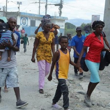 Moradores caminham por uma rua enquanto fogem de suas casas em Cité Soleil, após confrontos entre gangues rivais na capital do Haiti 