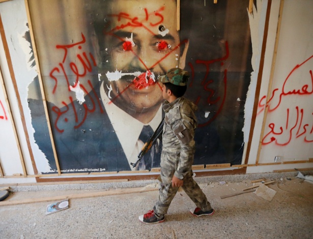 Combatentes da organização xiita Badr olham pôster de Saddam Hussein - Thaier Al-Sudani/Reuters