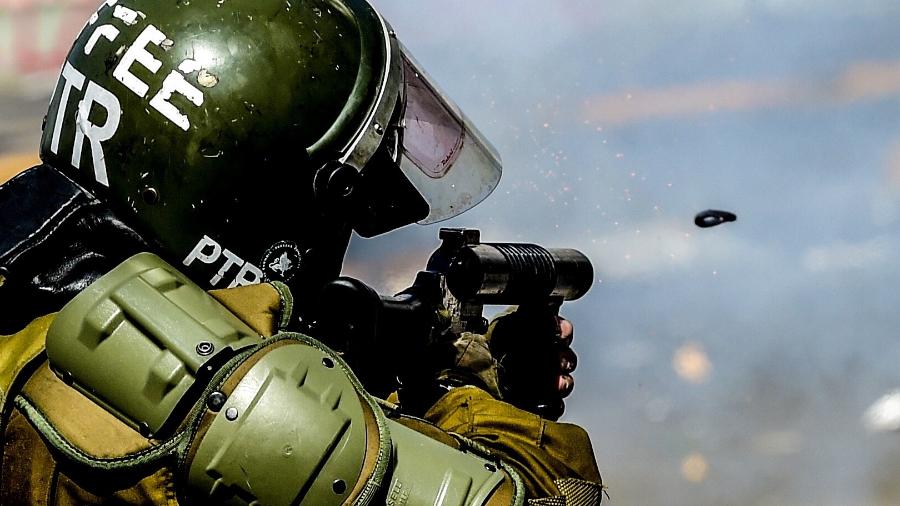 21.out.2019 - Policial atira contra manifestantes durante os protestos em Santiago, no Chile - Martin Bernetti/AFP