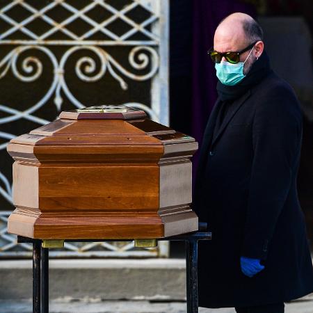 20.mar.2020 - Homem ajuda a carregar caixão durante funeral na Itália - Piero Cruciatti / AFP