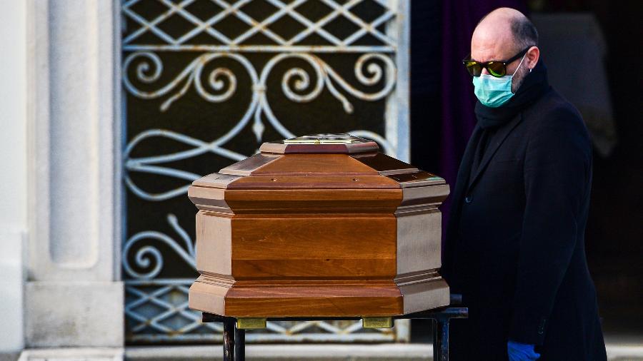 Homem ajuda a carregar caixão durante funeral na Itália; país foi um dos mais afetados pelo coronavírus - Piero Cruciatti / AFP