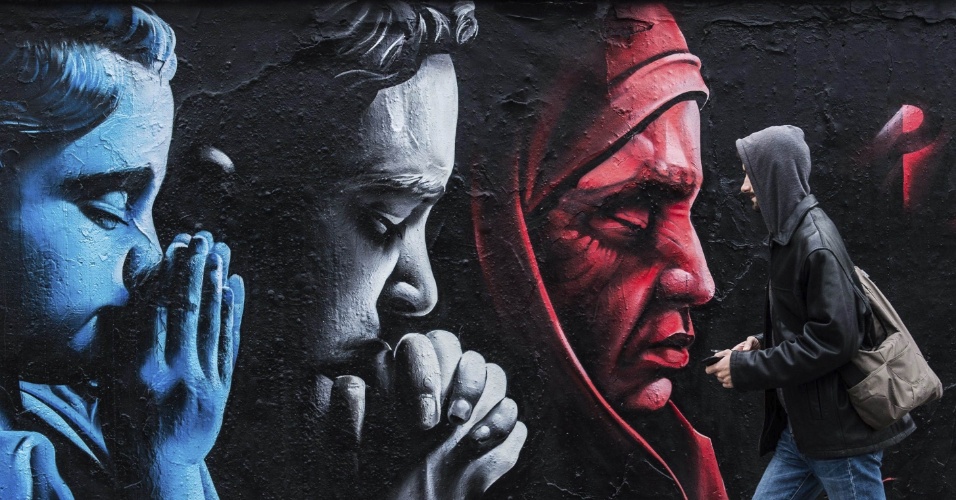 18.nov.2015 - Homem caminha ao lado de um graffiti que homenageia as vítimas dos ataques em Paris, feito pelo artista cazaque "Chemie", em Praga (República Tcheca)