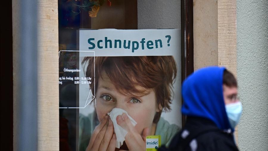 8.nov.2021 - Um homem para diante de anúncio de remédio para resfriado enquanto espera na fila do centro de vacinação em Radeberg, no leste da Alemanha - Tobias Schawrz/AFP