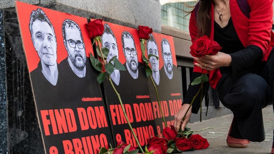 Mulher coloca uma rosa perto de cartaz com as imagens de Dom e Bruno - Divulgação/Brazil Matters