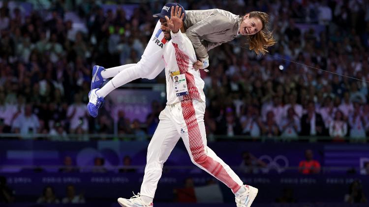 Após conquistar seu primeiro ouro olímpico na esgrima, a francesa Manon Apithy Brunet é levantada em comemoração pelo seu marido Bolade Apithy