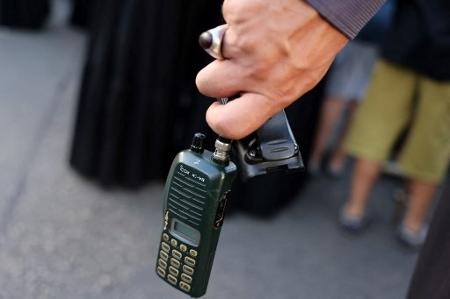 Um homem segura um walkie-talkie depois de remover a bateria durante o funeral de pessoas mortas no dia anterior