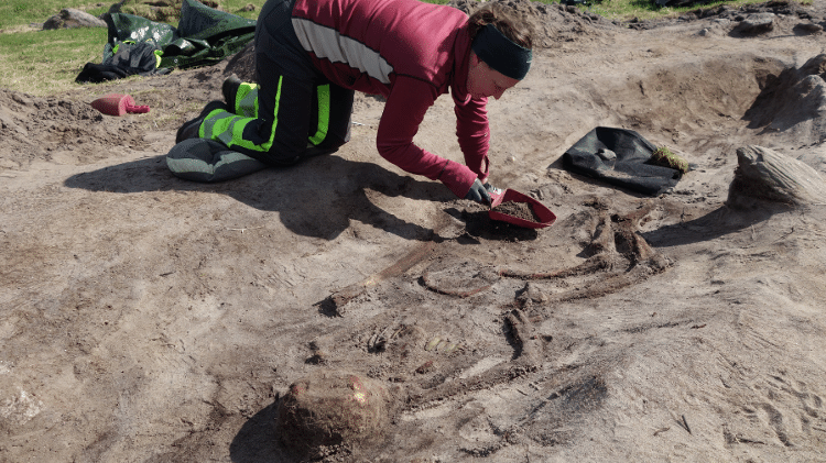 Arqueóloga trabalha no local para escavar os restos mortais e os objetos encontrados Arqueóloga trabalha no local para escavar os restos mortais e os objetos encontrados
