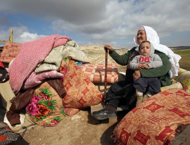 Palestina que teve a casa demolida pelo Exército de Israel senta-se ao lado dos objetos pessoais que restaram, em Hebron, na Cisjordânia - Hazem Bader/AFP 