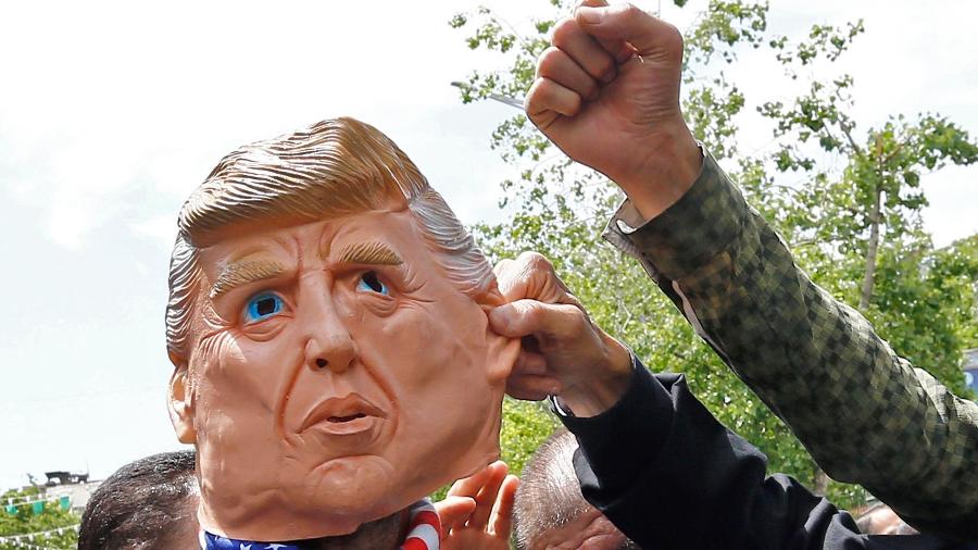 10.mai.2019 - Manifestantes iranianos puxam orelha de máscara de Donald Trump, presidente americano que impôs sanções ao Irã - AFP