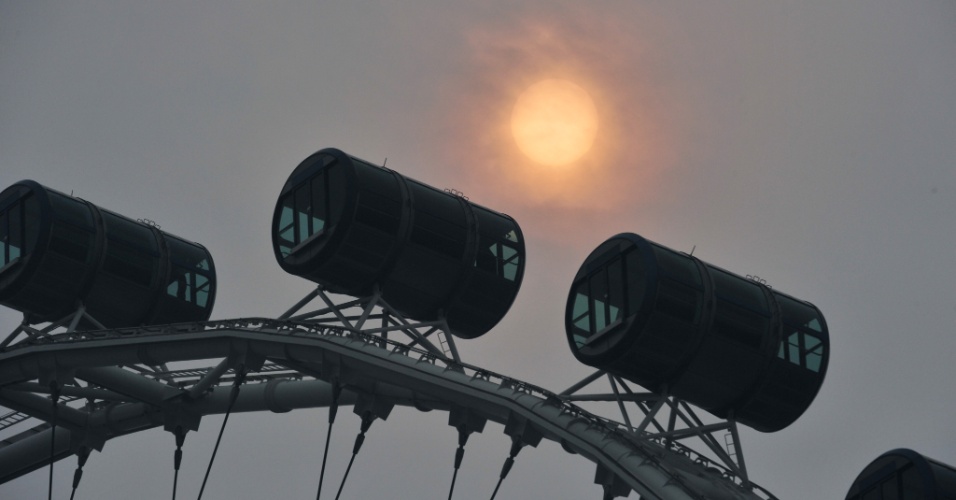 5.out.2015 - Neblina encobre o Sol atrás de roda gigante, em Marina Bay, Cingapura