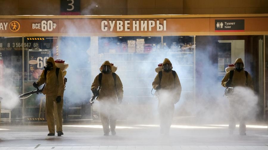 Funcionários do Ministério de Emergências da Rússia com roupa de proteção desinfetam estação de metrô - Moscow News Agency