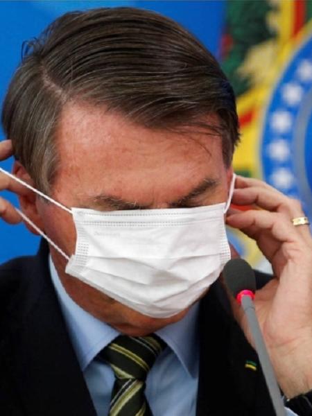 Bolsonaro cobre os olhos com máscara  - Adriano Machado/Reuters
