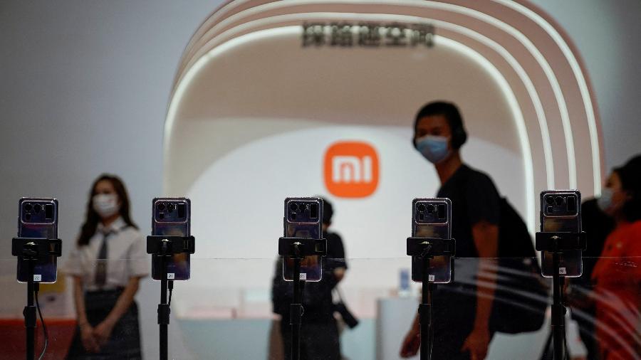 Homem observa telefones da Xiaomi durante evento em Xangai, na China