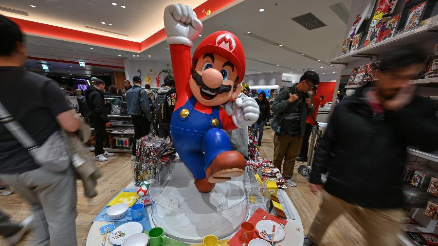 Pessoas passam por estátua do Super Mario, em loja da Nintendo em Tóquio, no Japão Pessoas passam por estátua do Super Mario, em loja da Nintendo em Tóquio, no Japão