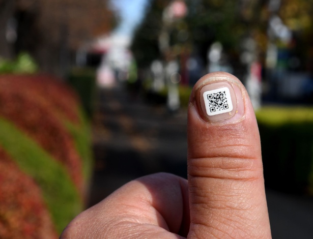 Funcionário da prefeitura mostra código QR na unha próximo à cidade de Iruma, Saitama (Japão) - Toshifumi Kitamura/AFP