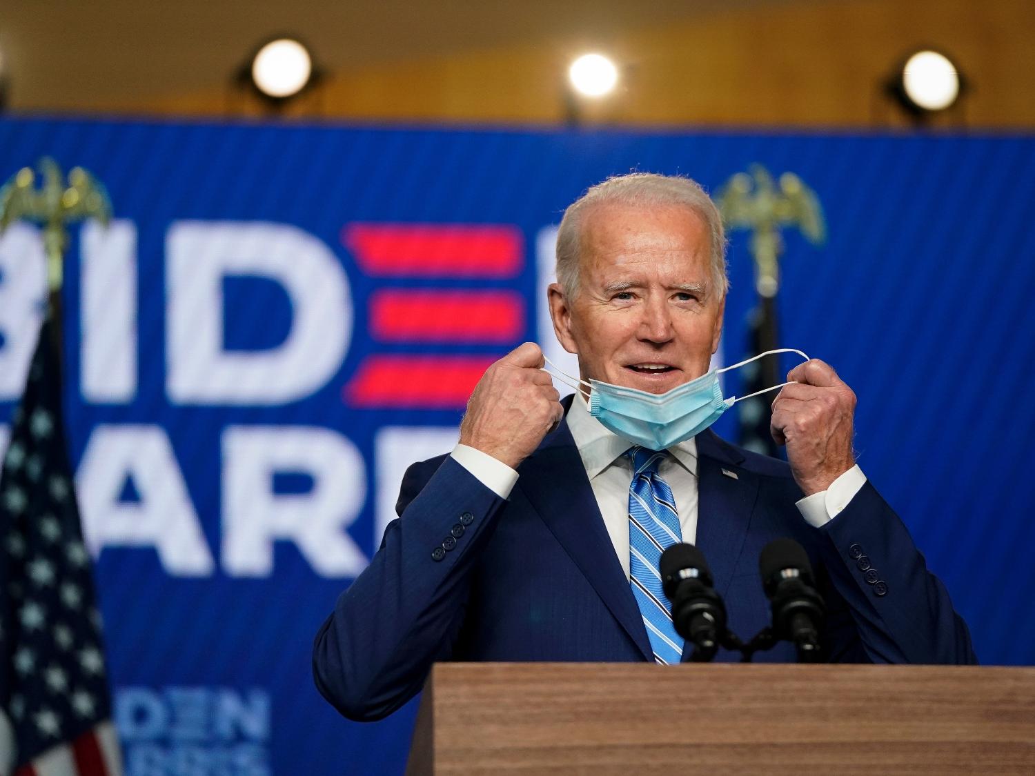 O candidato democrata à presidência, Joe Biden, tira a máscara ao chegar para falar um dia depois que os americanos votaram na eleição presidencial - Drew Angerer/ Getty Images/ AFP