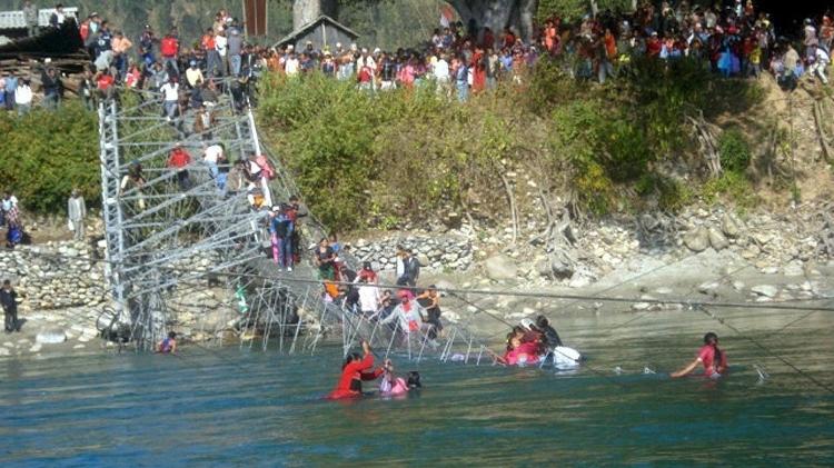 Pessoas tentam sair das águas do rio Bheri, no Nepal, depois que uma ponte de aço suspensa despencou sobre o rio, em 25 de dezembro de 2007