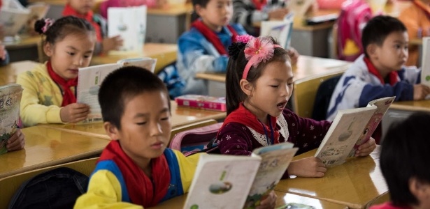 9.out.2015 - Crianças leem livros em escola primária do condado de Pingjiang, província de Hunan, China, no primeiro dia de volta às aulas - Johannes Eisele/AFP