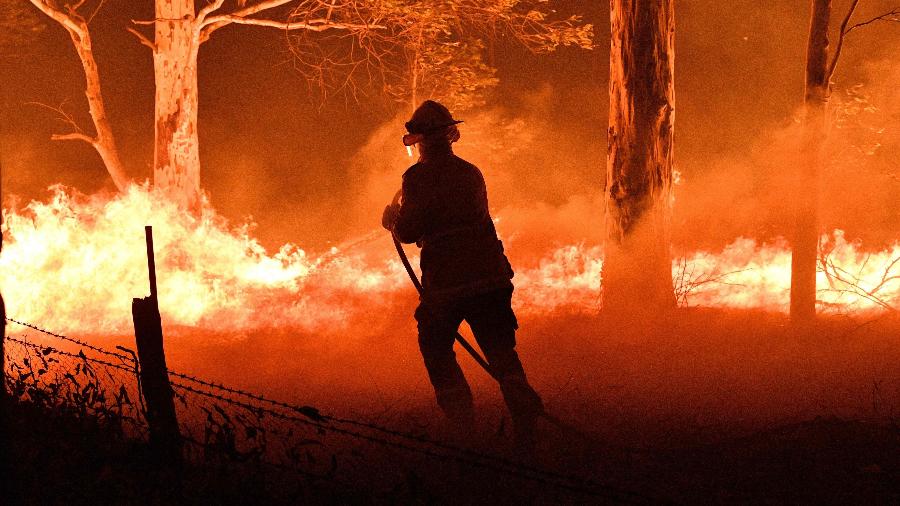 Bombeiro tenta proteger casas de incêndio floretal na Austrália no último dia do ano passado - Saeed Khan - 31.dez.2019/AFP