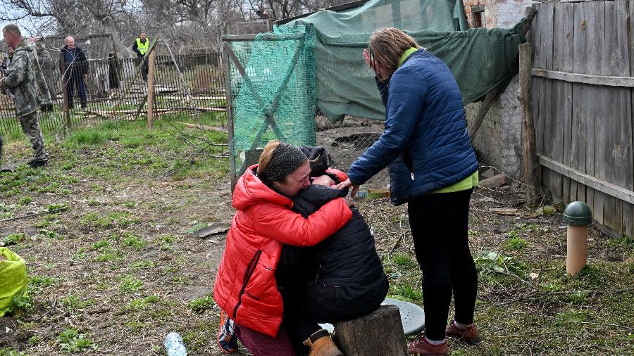 Parentes reagem após descobrirem corpo enterrado no quintal de casa em Andrivka, perto de Kiev, em meio ao conflito entre Rússia e Ucrânia - Sergei Supinsky/AFP