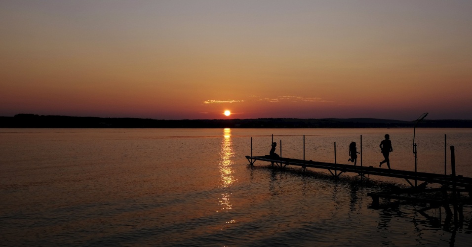 08.set.2015 - Crianças brincam em um cais enquanto o sol se põe sobre Long Lake, no Maine (EUA)