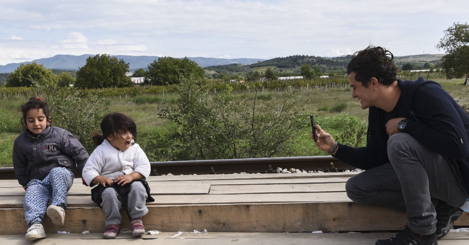 28.set.2015 - O ator britânico Orlando Bloom, embaixador da Boa Vontade do Unicef, tira fotografia de crianças em visita a campo de refugiados em Gevgelija, Macedônia