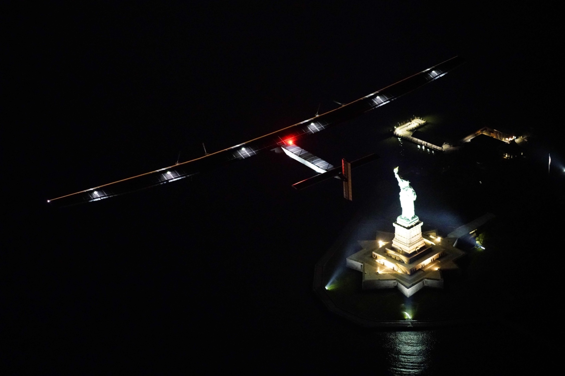 20.jun.2016 - O avião Solar Impulse 2 sobrevoa a Estátua da Liberdade, em Nova York, EUA. O avião iniciou nesta segunda-feira em Nova York uma perigosa travessia transatlântica de quatro dias como parte de sua volta ao mundo para promover as energias renováveis - Solar Impulse 2/ Jean Revillard/ Rezo/ AFP
