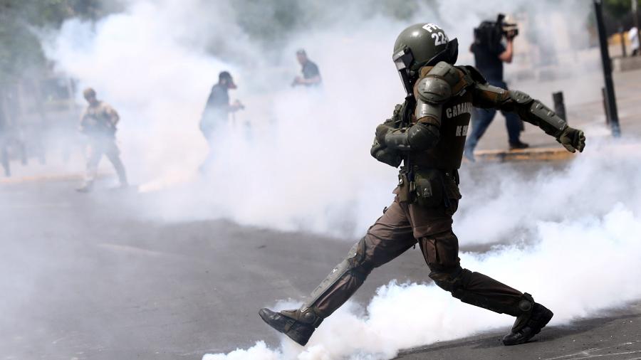 Policial chuta lata de gás lacrimogênio durante protestos em Santiago, no Chile - Edgard Garrido/Reuters