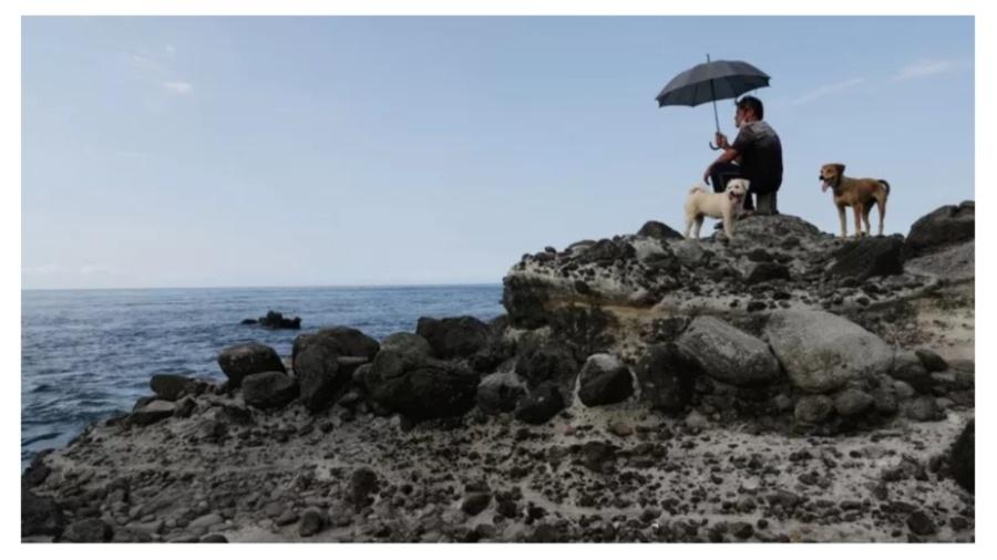 Homem observa exercícios militares chineses no litoral de Taiwan - EPA
