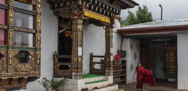 Um jovem monge entra no templo Chimi Lhakhang para as orações da manhã, perto de Lobesa, no Butão - Gilles Sabrié/The New York Times