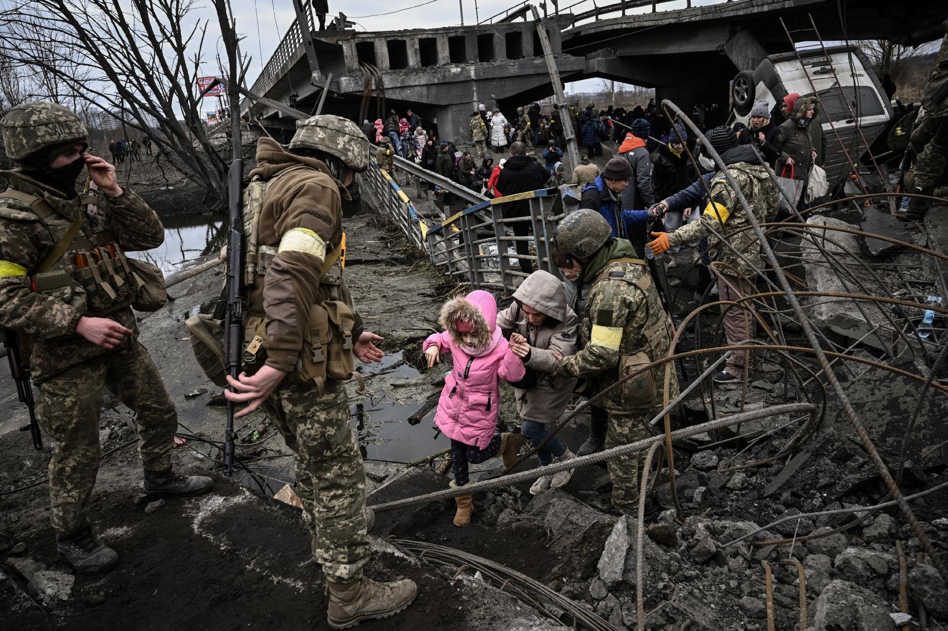 March 5, 2022 - People cross a destroyed bridge as they evacuate the town of Irpin, northwest of Kiev - March 5, 2022 - Aris Messinis/AFP