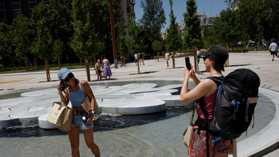 10.jul.2022 - Turista posa para foto enquanto se refresca em fonte de água durante onda de calor em Madri, na Espanha - Susana Vera/Reuters