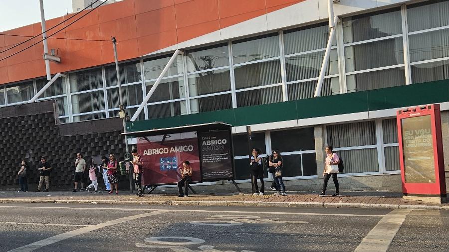 Passageiros em um ponto de ônibus na zona oeste de São Paulo na tarde de quinta-feira (12)