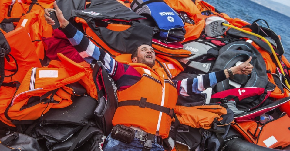 2.out.2015 - Imigrante celebra chegada a salvo em cima de um monte de coletes salva-vidas depois de pegar um bote para alcançar a ilha de Lesbos, na Grécia